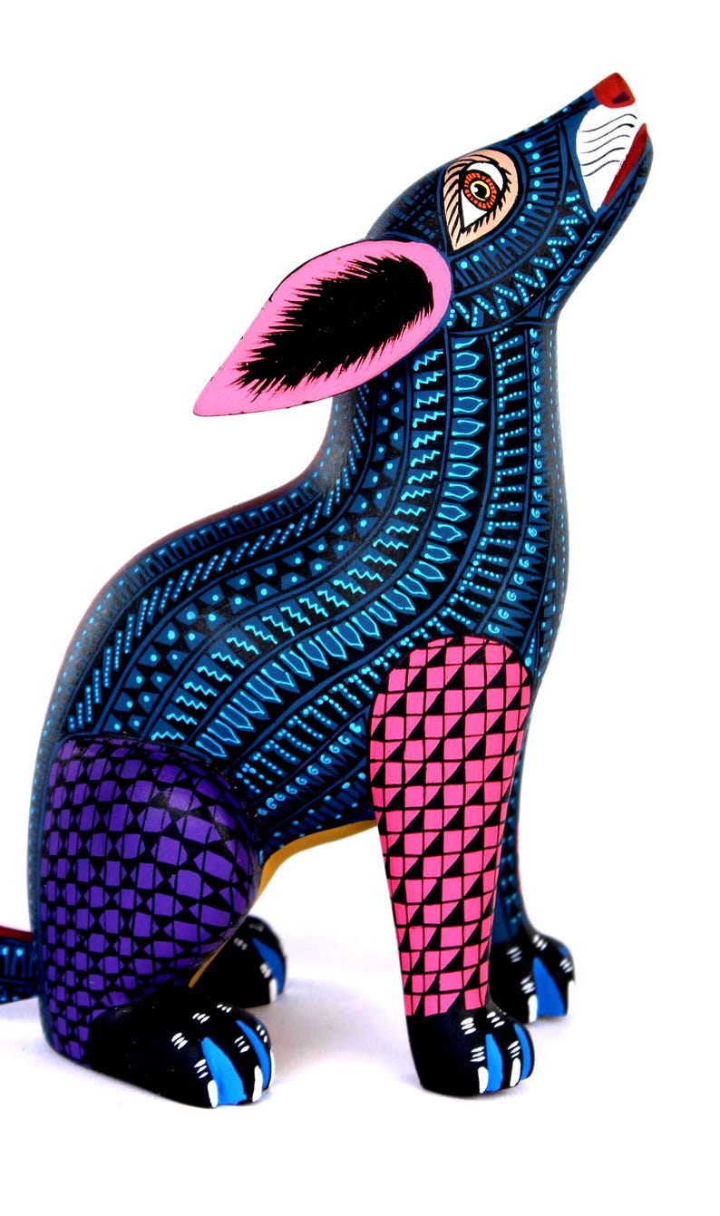 May include: A hand-painted wooden dog figurine featuring a dark blue base color with intricate light blue geometric patterns. The ears are bright pink with black centers, the front leg is pink with black triangles, and the back leg is purple with black squares.