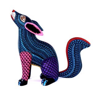 May include: A hand-painted wooden coyote figurine featuring a dark blue body covered in intricate light blue patterns. The front legs are pink with black triangles, the hindquarters are purple with a grid pattern, and the tail has red edges.