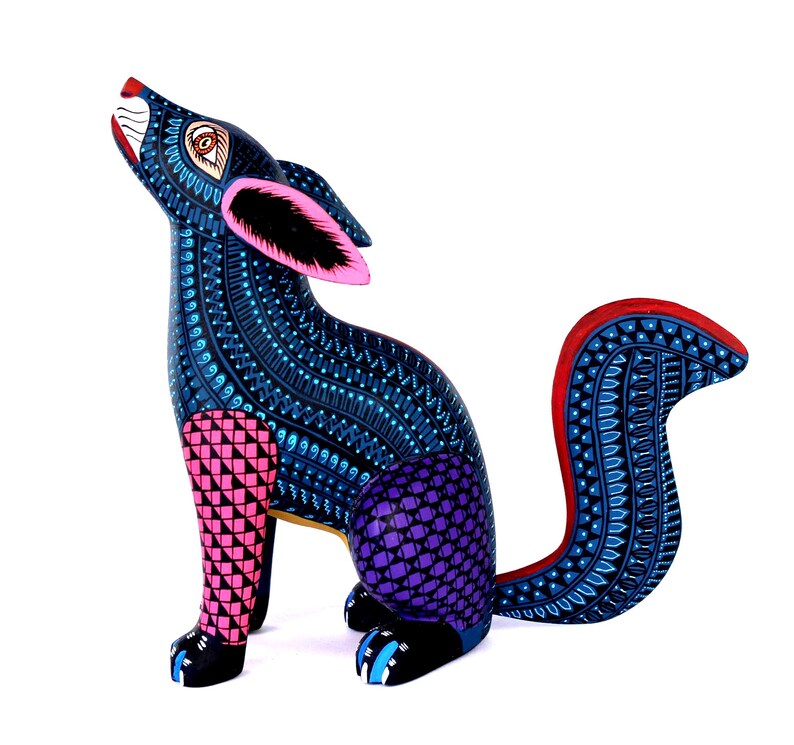 May include: A hand-painted wooden coyote figurine featuring a dark blue body covered in intricate light blue patterns. The front legs are pink with black triangles, the hindquarters are purple with a grid pattern, and the tail has red edges.