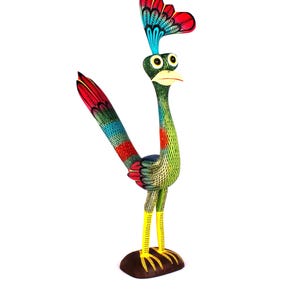 May include: A hand-painted wooden bird figurine featuring a vibrant green body with intricate black cross-hatching patterns, a long tail with red and blue feathers, a tall crest, yellow legs, and large white eyes with black pupils standing on a base.