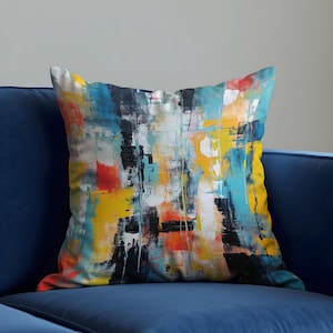 May include: A colourful abstract throw pillow with a blue, yellow, orange, and black design. The pillow is made of soft fabric and is perfect for adding a touch of modern style to any room.