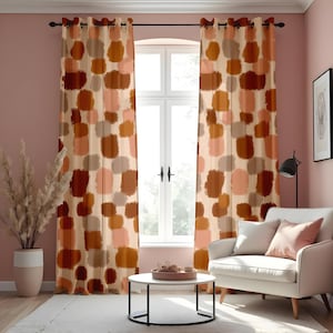 Può includere: Un paio di tende marroni, beige e rosa con motivo geometrico e occhielli in alto, appese in un soggiorno con una poltrona bianca e un tavolino da caffè.