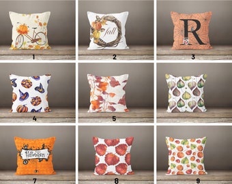 May include: Nine different throw pillow designs featuring fall and Halloween themes. The designs include pumpkins, leaves, a bicycle, a spiderweb, a witch's hat, and the word "fall".