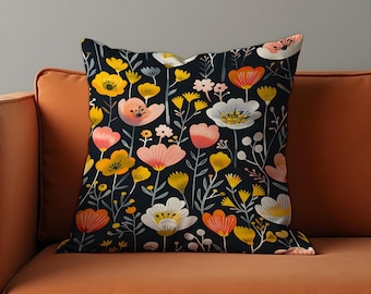 Könnte beinhalten: Quadratisches Kissen mit floralem Muster. Das Design zeigt einen dunklen Hintergrund mit bunten Blumen in Gelb-, Orange-, Rosa- und Weißtönen. Das Kissen liegt auf einem orangefarbenen Sofa.