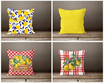 May include: Four different pillow designs featuring lemons and a gingham pattern. The first pillow has a white background with yellow lemons and blue leaves. The second pillow is yellow with white stripes. The third pillow has a red and white gingham pattern with a basket of lemons. The fourth pillow has a red and white gingham pattern with lemons on a branch.