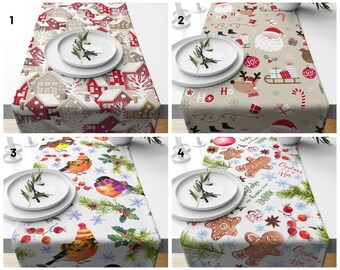 May include: Four different Christmas table runner designs. The first runner features a snowy village scene with red and white houses. The second runner has a beige background with a repeating pattern of Santa Claus, reindeer, and Christmas presents. The third runner has a white background with a watercolor design of birds, holly, and snowflakes. The fourth runner has a white background with a watercolor design of gingerbread men, holly, and cinnamon sticks.