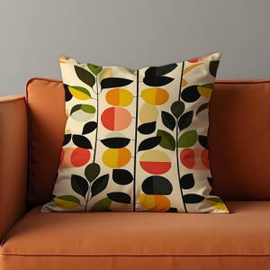 May include: A cream-coloured throw pillow with a geometric pattern of black, green, yellow, red, and pink circles and leaves.