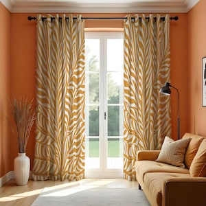 Può includere: Tende a motivi giallo senape e bianchi con un design a foglie, appese davanti a una finestra bianca. Le tende sono sospese a un'asta nera. La stanza ha pareti arancioni e un divano beige. Le tende sono lunghe circa 200 cm.