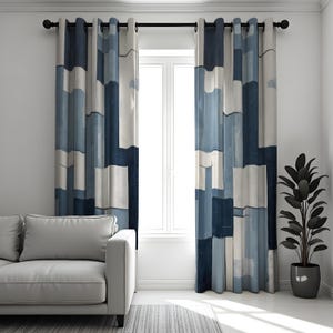 Op de afbeelding: Een paar blauw-wit gordijnen met een geometrisch patroon. De gordijnen hangen voor een raam, met een witte bank en een plant in pot in de kamer. De gordijnen hebben een stangzak.