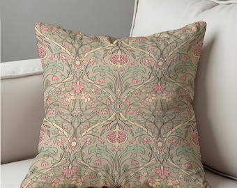 May include: Square decorative pillow with a repeating floral pattern in shades of beige, pink, green, and yellow. The design features stylized flowers, leaves, and pomegranate motifs. The pillow is placed on a white sofa.