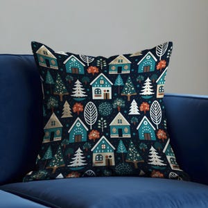 Könnte beinhalten: Quadratisches Kissen mit einem sich wiederholenden Muster aus türkisfarbenen Häusern, weißen Bäumen und orangefarbenen Bäumen auf dunkelblauem Hintergrund. Das Kissen liegt auf einem dunkelblauen Sofa.