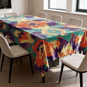 May include: A rectangular tablecloth with a vibrant geometric pattern in shades of teal, orange, purple, and yellow. The tablecloth is draped over a dining table, with several chairs surrounding it. The design features abstract shapes.