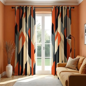 May include: Pair of patterned curtains with a geometric design in orange, black, grey, and beige. The curtains are hanging in front of a window. The design features angled lines and shapes.