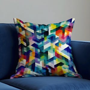 Op de afbeelding: Vierkant sierkussen met een levendig geometrisch patroon in tinten blauw, geel, oranje, paars en wit. Het kussen ligt op een donkerblauwe bank en vormt een kleurrijk accent voor de woondecoratie.