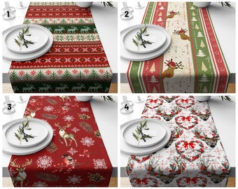 May include: Four different Christmas table runners with various designs. The first runner features a red and green Scandinavian-style pattern with reindeer. The second runner has a red, green, and cream striped pattern with a reindeer and the words "Merry Christmas" and "Happy Holidays". The third runner has a red background with a white snowflake pattern and a reindeer. The fourth runner has a white background with a red heart wreath pattern and a reindeer.