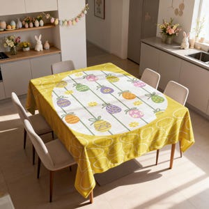 May include: A rectangular yellow Easter tablecloth with a white center featuring colorful Easter egg designs. The tablecloth is set on a wooden table with four chairs. The room has a kitchen setting with Easter decorations.