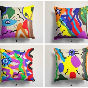 May include: Four colourful throw pillow covers with abstract designs featuring bright colours like yellow, red, blue, green, and purple. Each pillow cover has a unique design with a central eye motif.