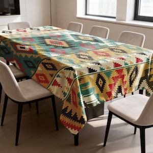 May include: A rectangular tablecloth with a Southwestern-inspired geometric pattern. The design features repeating diamond and zigzag motifs in shades of teal, red, yellow, and black. The tablecloth is draped over a large dining table.