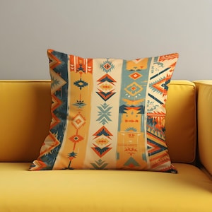 Puede incluir: Cojín decorativo cuadrado con un colorido patrón geométrico en tonos naranja, turquesa y crema. El cojín está colocado sobre un sofá amarillo, mostrando su diseño y textura. El patrón presenta formas de inspiración tribal.