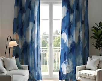 Può includere: Un paio di tende a motivi blu e bianchi con un design astratto sono appese in un soggiorno con un divano bianco e una poltrona bianca.