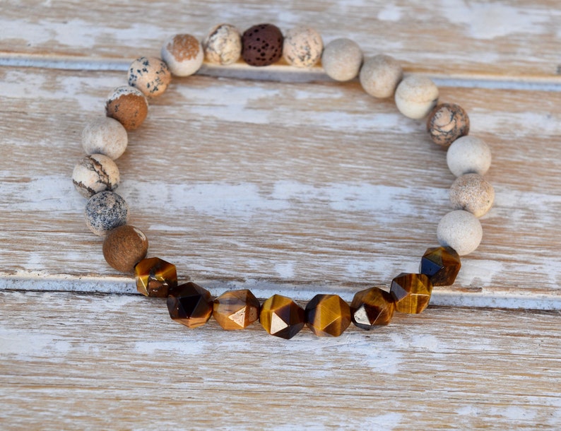 May include: A brown and gold beaded bracelet with tiger's eye gemstone beads. The bracelet is made with natural stones and has a simple design.