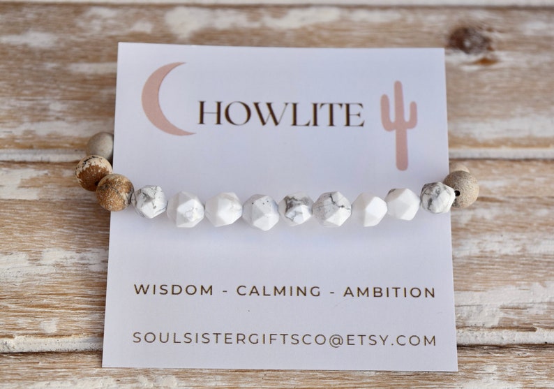 Op de afbeelding: Witte howliet-stenen armband met bruine en witte kralen. De armband ligt op een witte kaart met de tekst "HOWLITE", "WISDOM - CALMING - AMBITION" en "SOULSISTERGIFTSCO@ETSY.COM".