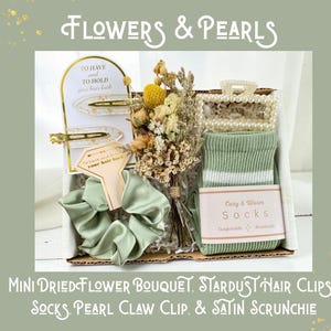 May include: A gift box with a mini dried flower bouquet, stardust hair clips, socks, a pearl claw clip, and a satin scrunchie. The box includes a pair of green socks with white stripes and a light green satin scrunchie.