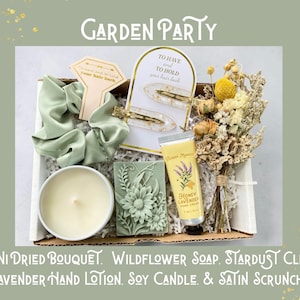 May include: A gift box labeled "Garden Party" containing a mini dried bouquet, wildflower soap, stardust clips, lavender hand lotion, a soy candle, and a satin scrunchie. The box includes a light green satin scrunchie and a bar of green soap with a floral design.