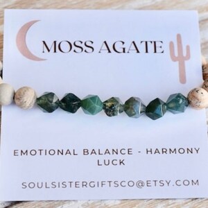 May include: A green moss agate bracelet with white and brown jasper beads. The bracelet is on a white card with the text "Moss Agate", "Emotional Balance - Harmony", "Luck", and "Soulsistergiftsco@etsy.com".