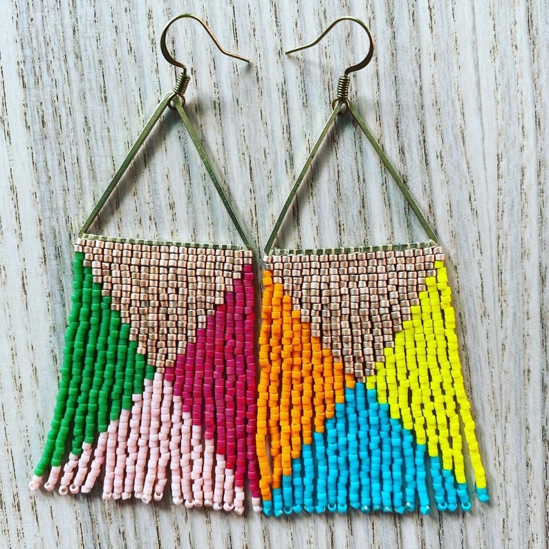 May include: Two pairs of triangle shaped earrings with gold hoops and colorful beaded fringe. One pair has pink, green, and red beads, and the other pair has yellow, blue, and orange beads.