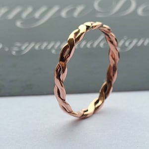 May include: A rose gold braided ring. The ring is simple and elegant.