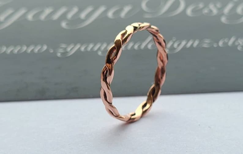 May include: A rose gold braided ring. The ring is simple and elegant.