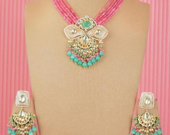 May include: A pink and green beaded necklace set with a large, ornate pendant and matching earrings. The pendant features a floral design with green and white stones.