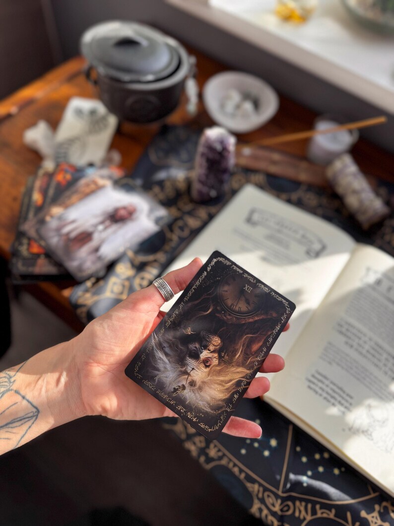 May include: A tarot card with a detailed illustration of a woman with long hair, a clock, and ornate borders. The card is held in a hand, with other mystical items like books and crystals in the background.