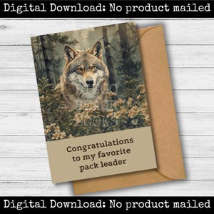 Puede incluir: Tarjeta de felicitación con una ilustración detallada de un lobo en un entorno forestal. La tarjeta tiene una pancarta beige con el texto "Felicitaciones a mi líder de manada favorito". Incluye un sobre marrón.