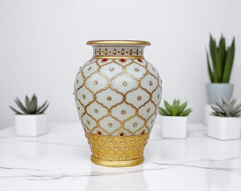 Könnte beinhalten: Eine weiße Keramikvase mit einem goldenen und roten geometrischen Muster. Die Vase hat einen runden Körper und einen schmalen Hals.