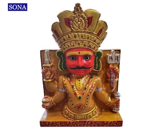May include: A wooden statue of a Hindu deity with a red face, gold crown, and multiple arms holding various objects. The statue is painted with intricate details and has a gold background.