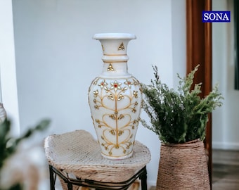 Könnte beinhalten: Weiße Marmorvase mit goldenen und roten floralen Designs. Die Vase hat eine breite Öffnung und einen schmalen Boden.