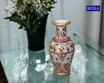 Könnte beinhalten: Weiße Marmorvase mit goldenen und roten floralen Designs. Die Vase hat einen runden Körper und einen schmalen Hals.