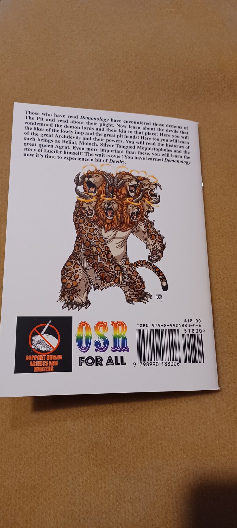 May include: A book cover with a colorful illustration of a multi-headed beast with glowing halos. The book title is "OSR For All" and the text "Support Human Artists and Writers" is in a red circle with a diagonal line through it. The book cover also includes the ISBN number and barcode.