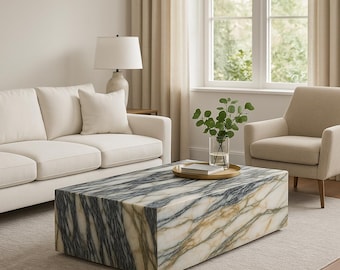 May include: A large, rectangular coffee table with a white marble top and black and gold veining. The table is sitting on a light gray rug in a living room.