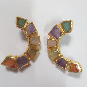 Puede incluir: Un par de pendientes de oro con un diseño semicircular que presenta una variedad de piedras preciosas de colores, incluyendo amatista, cornalina y verde.