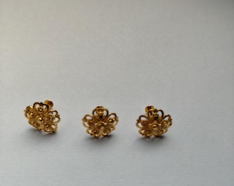 May include: Three gold-toned stud earrings, each featuring a delicate, openwork floral design with intricate filigree patterns and a small, raised central bead. The earrings are arranged in a horizontal row, showcasing a polished metallic finish.