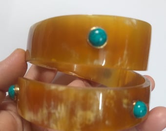 May include: Two brown horn bracelets with turquoise stones set in gold.