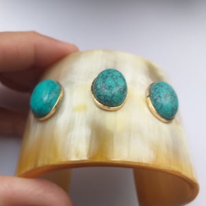 May include: A gold cuff bracelet with three turquoise stones set in gold.