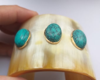 May include: A gold cuff bracelet with three turquoise stones set in gold.