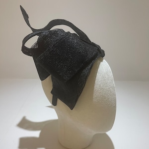 May include: Black mesh headband with a large bow. The headband is on a white mannequin head.