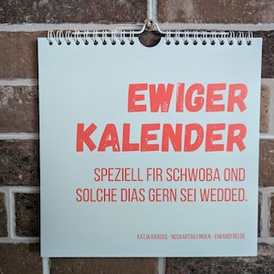 Könnte beinhalten: Ein weißer Kalender mit dem Text "EWIGER KALENDER" in Rot. Der Text darunter lautet "SPEZIELL FIR SCHWOBA OND SOLCHE DIAS GERN SEI WEDDED." und "KATJA KRAUSS - NECKARTAILFINGEN - EIWANDFRELDE".