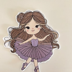 Könnte beinhalten: Gestickter Aufnäher mit einer Cartoon-Ballerina mit braunen Haaren, die zu einem Dutt hochgesteckt sind und herunterfallen. Sie trägt einen lila Body und Tutu mit passenden Ballettschuhen. Der Aufnäher hat einen weißen Rand.