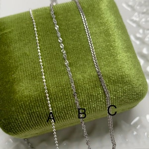 May include: Three silver chains of different styles, labelled A, B, and C, displayed on a green velvet surface.